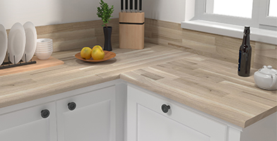 Plan de travail de cuisine moderne en bois clair, agrémenté de bocaux et ustensiles pour une esthétique naturelle et fonctionnelle.